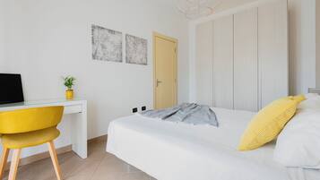 Una camera da letto con un letto, una scrivania con un computer, una sedia e una porta.
