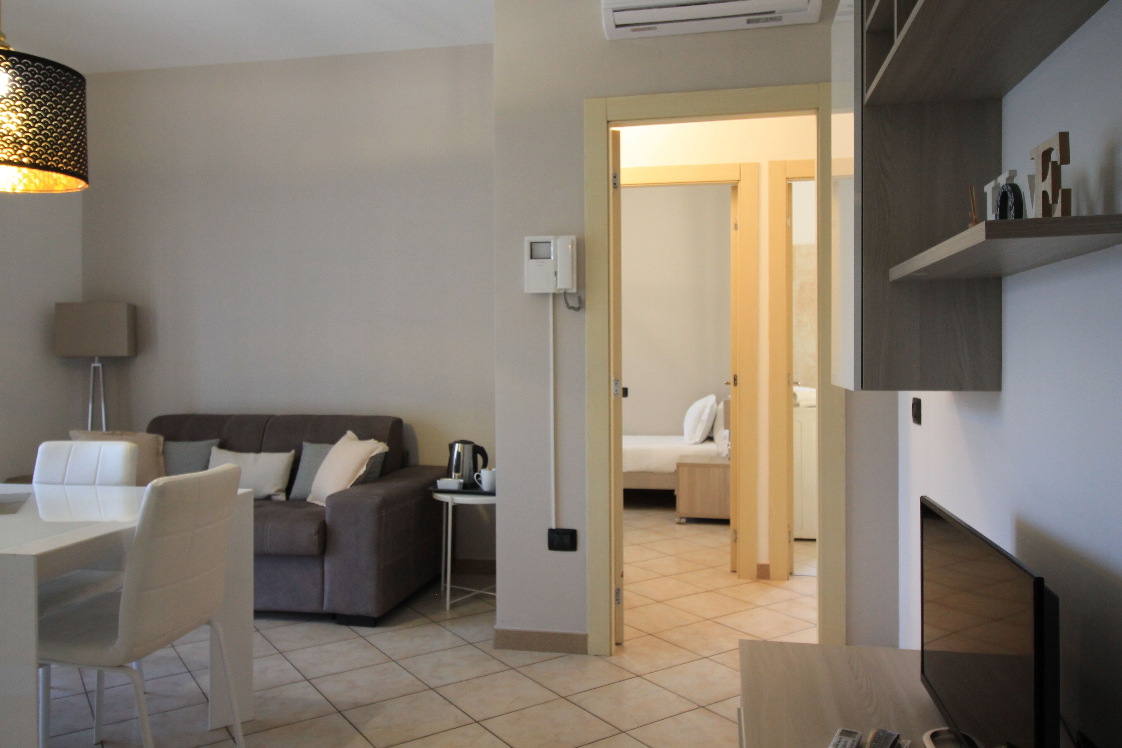 A modern hotel room with a sofa, dining table, and a TV.
