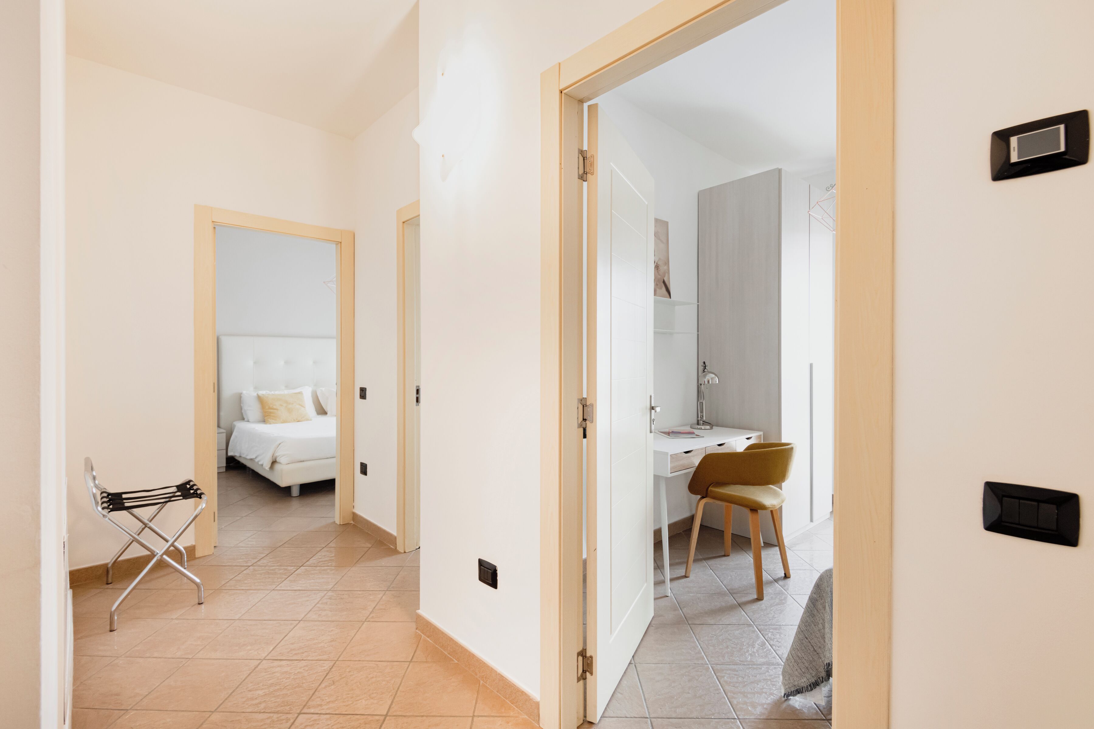 Een hotelkamer met een bed, een bureau en een stoel. Er is een klein tafeltje met een lamp en een raam met uitzicht.