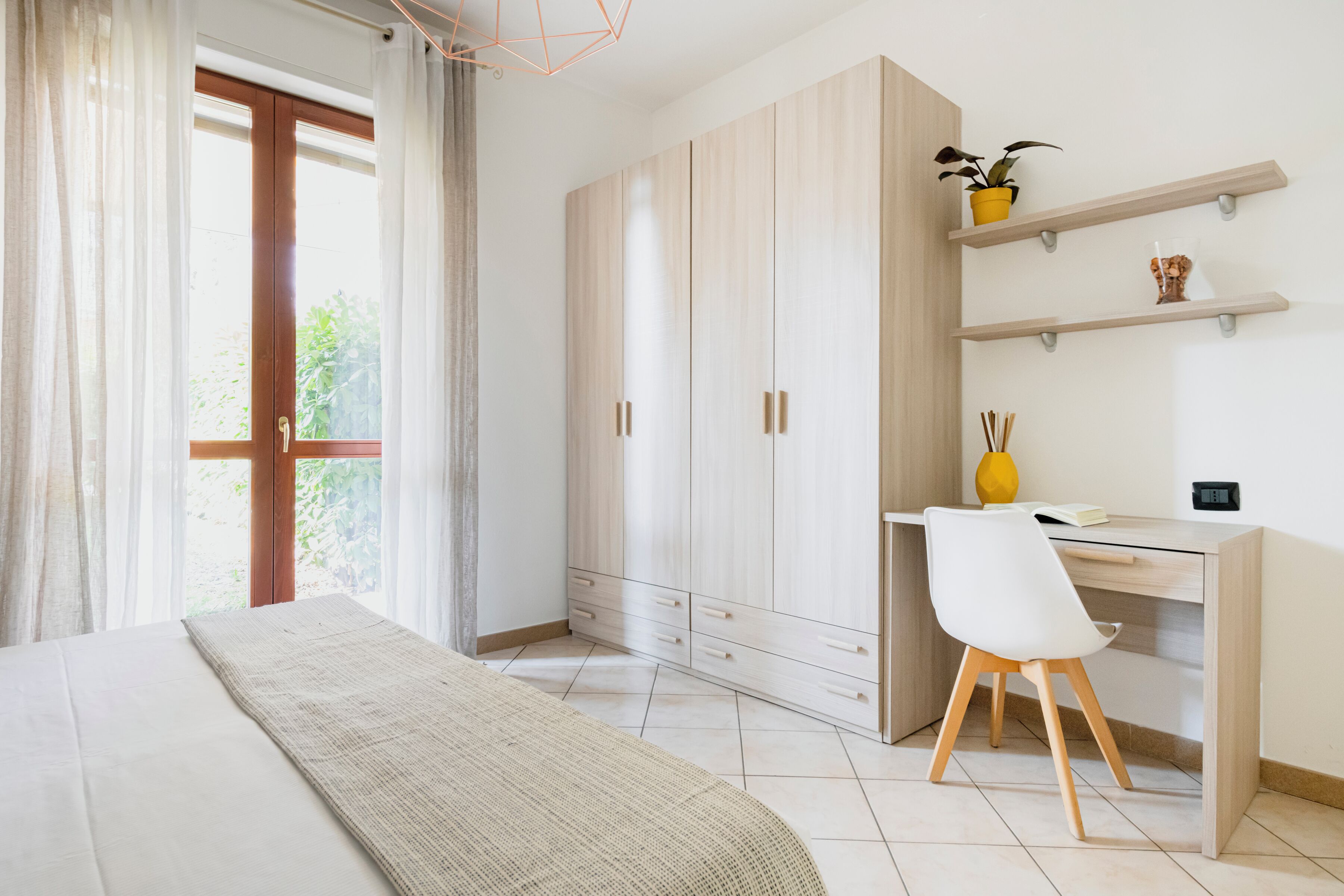 Quarto com cama, escrivaninha, cadeira e guarda-roupa.