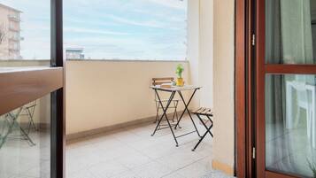 A balcony with a table, chairs, and a potted plant.