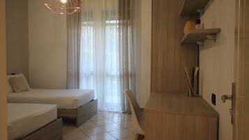 A bedroom with two beds, a desk, and a chair.