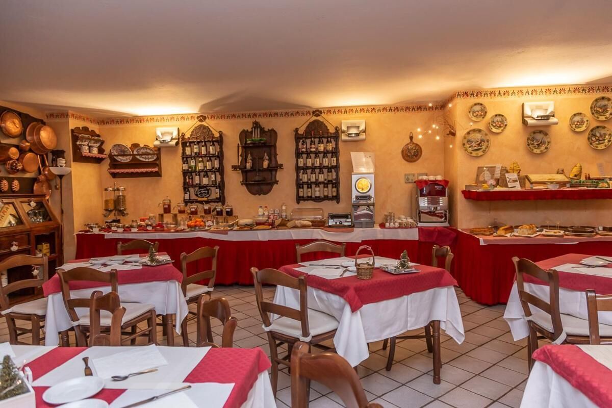 Un restaurant avec de nombreuses tables recouvertes de nappes rouges et blanches, des chaises en bois, et une variété de plats exposés sur des étagères et des comptoirs.