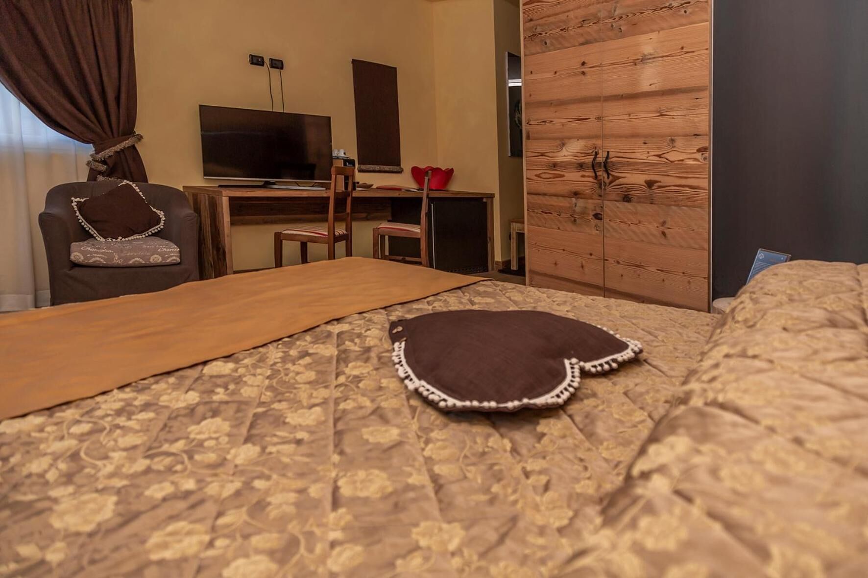 A hotel room with a bed, a desk, a television, and a wardrobe.