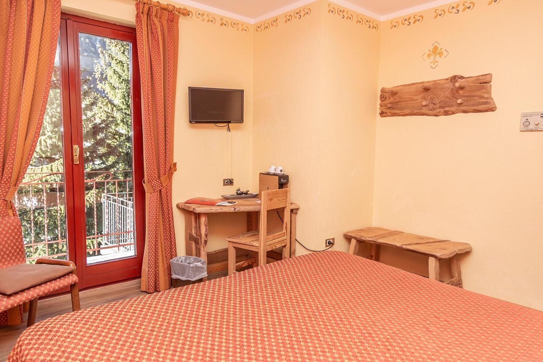A room with a bed, a desk, a chair, a TV, and a window with curtains.