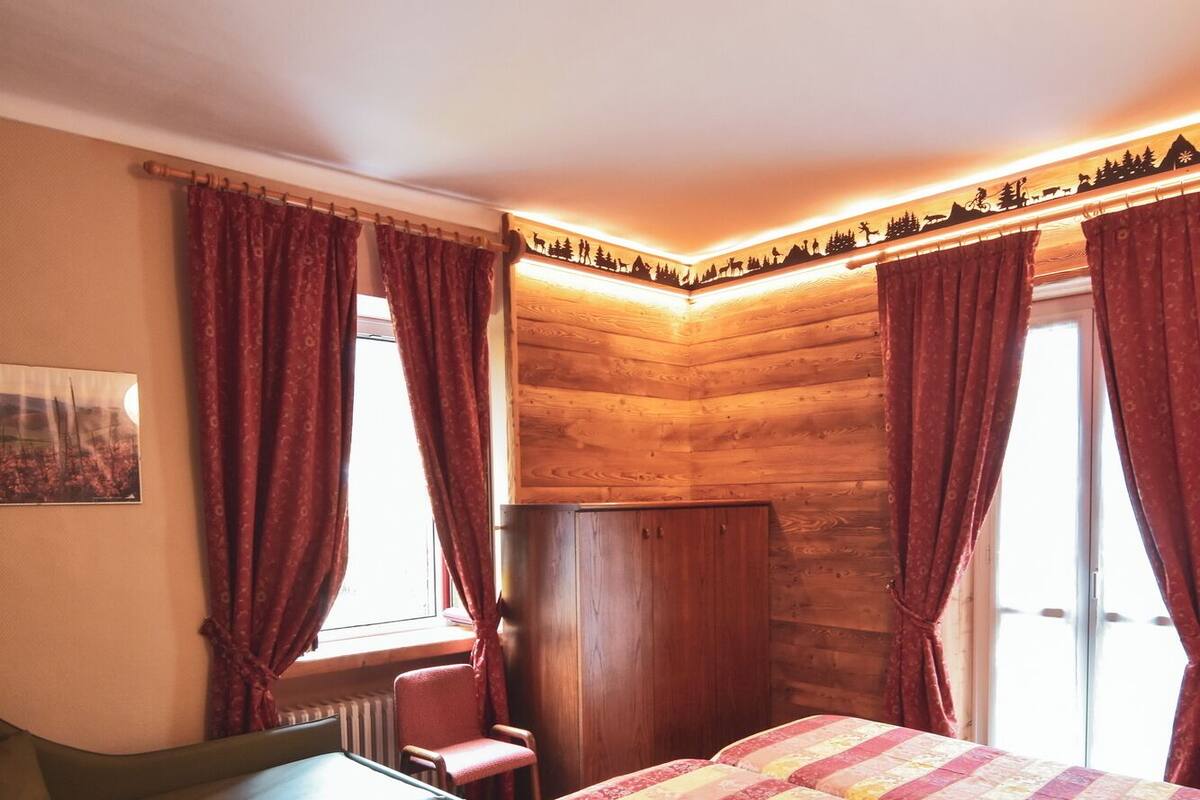 A cozy room with a bed, a chair, a small table, and a radiator.