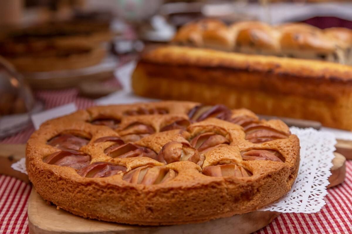 A round cake with a lattice top, placed on a wooden board with a lace doily underneath.