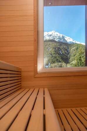 Un banco de madera con vista a una montaña nevada a través de una ventana.