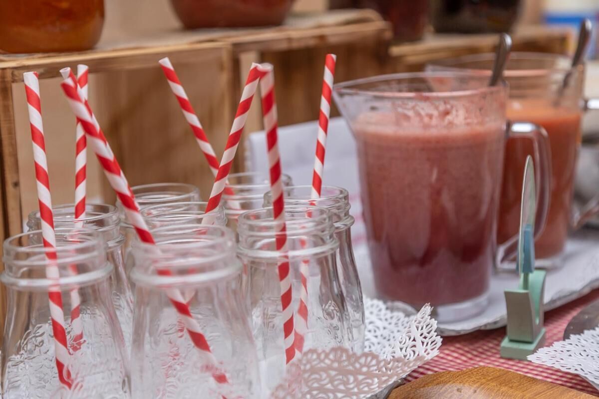 Et bord med glas og sugerør, samt en kande lyserød smoothie.