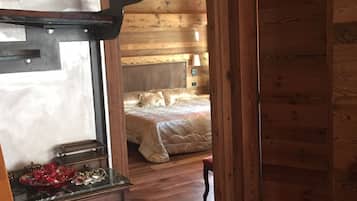 A wooden cabin interior with a bunk bed, a desk with a mirror, and a red rug.