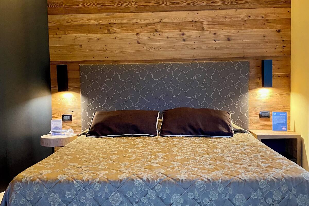 A bedroom with a wooden headboard, a bed with a floral duvet, and bedside tables with lamps.
