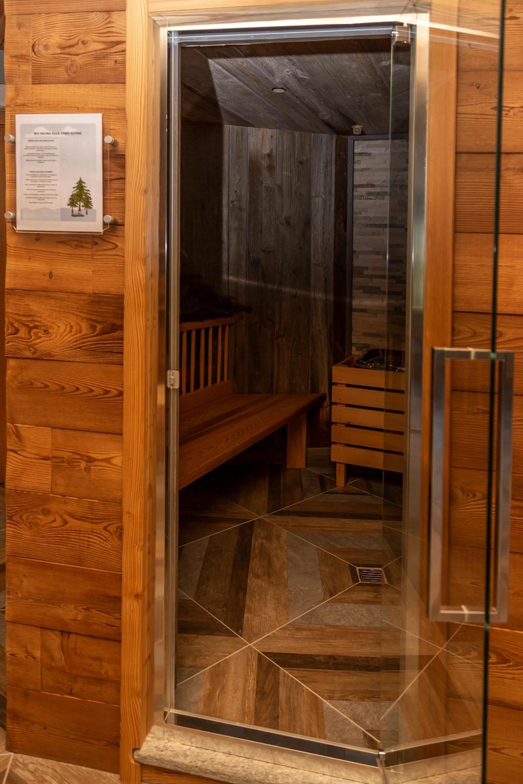Una cabaña de madera con un vidrio en la puerta que da a un cuarto con un banco y un pequeño cofre de madera.
