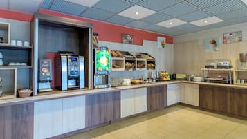 A modern breakfast bar with coffee machines, a juice dispenser, and a variety of breakfast items.