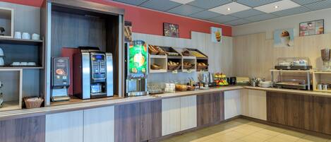 Un bar à petit-déjeuner moderne, équipé de machines à café, d’un distributeur de jus et proposant une variété d’aliments pour le petit-déjeuner.