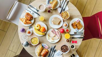 A round dining table with various breakfast items including croissants, toast, eggs, and fruits.