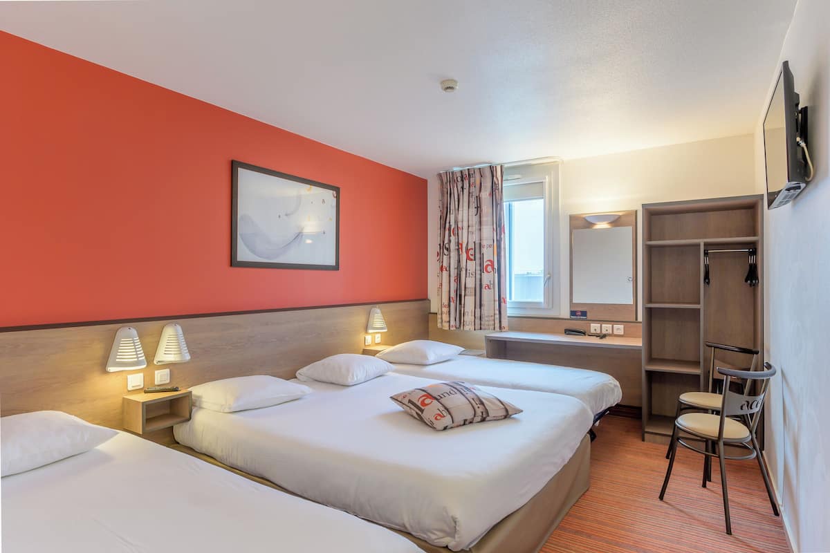 A hotel room with two beds, a desk, a chair, a wardrobe, a TV, and a painting on the wall.