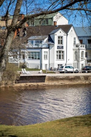 A hotel with a white facade, a balcony, and a view of a river. - Hotell Villa Rönne (Angelholm)