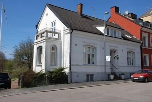 A white two-story building with a balcony on the first floor. - Hotell Villa Rönne (Angelholm)