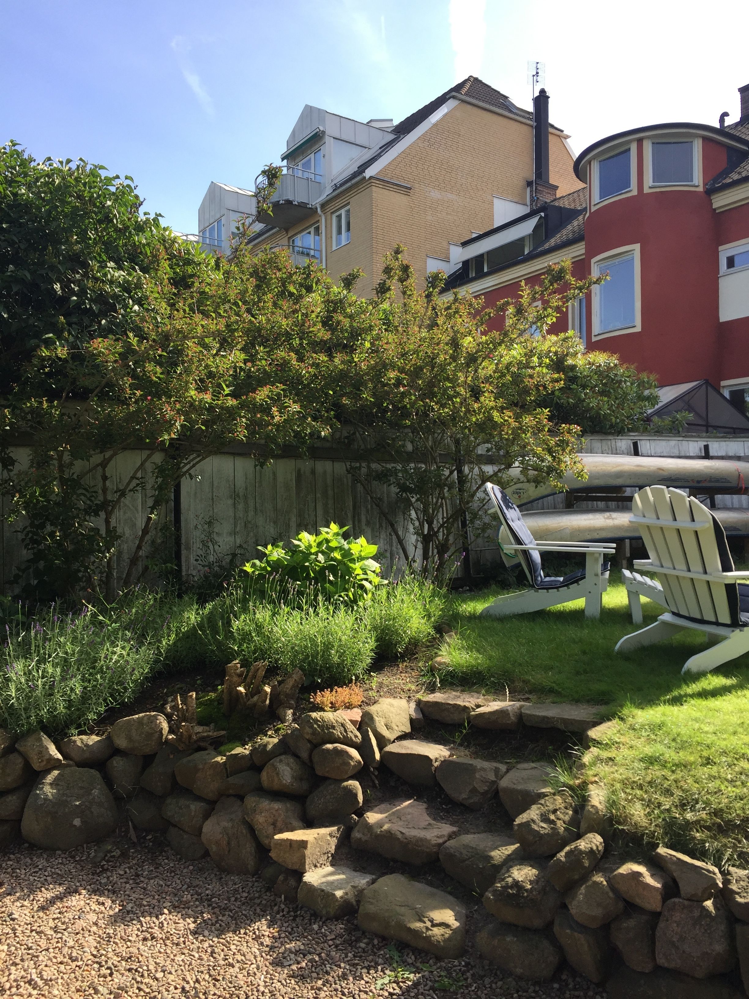 Een tuin met een houten omheining, een stoel en een kajak.