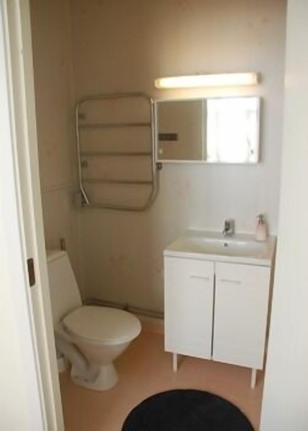 A small, compact bathroom with a toilet, a sink, and a mirror.