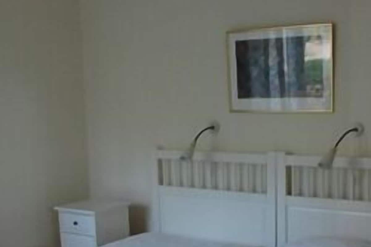 Un dormitorio con una cama doble, una mesita de noche y una repisa en la pared.