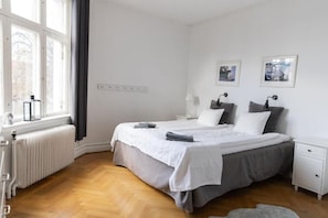 A bedroom with a bed, bedside tables, a radiator, and a window. - Hotell Villa Rönne (Angelholm)