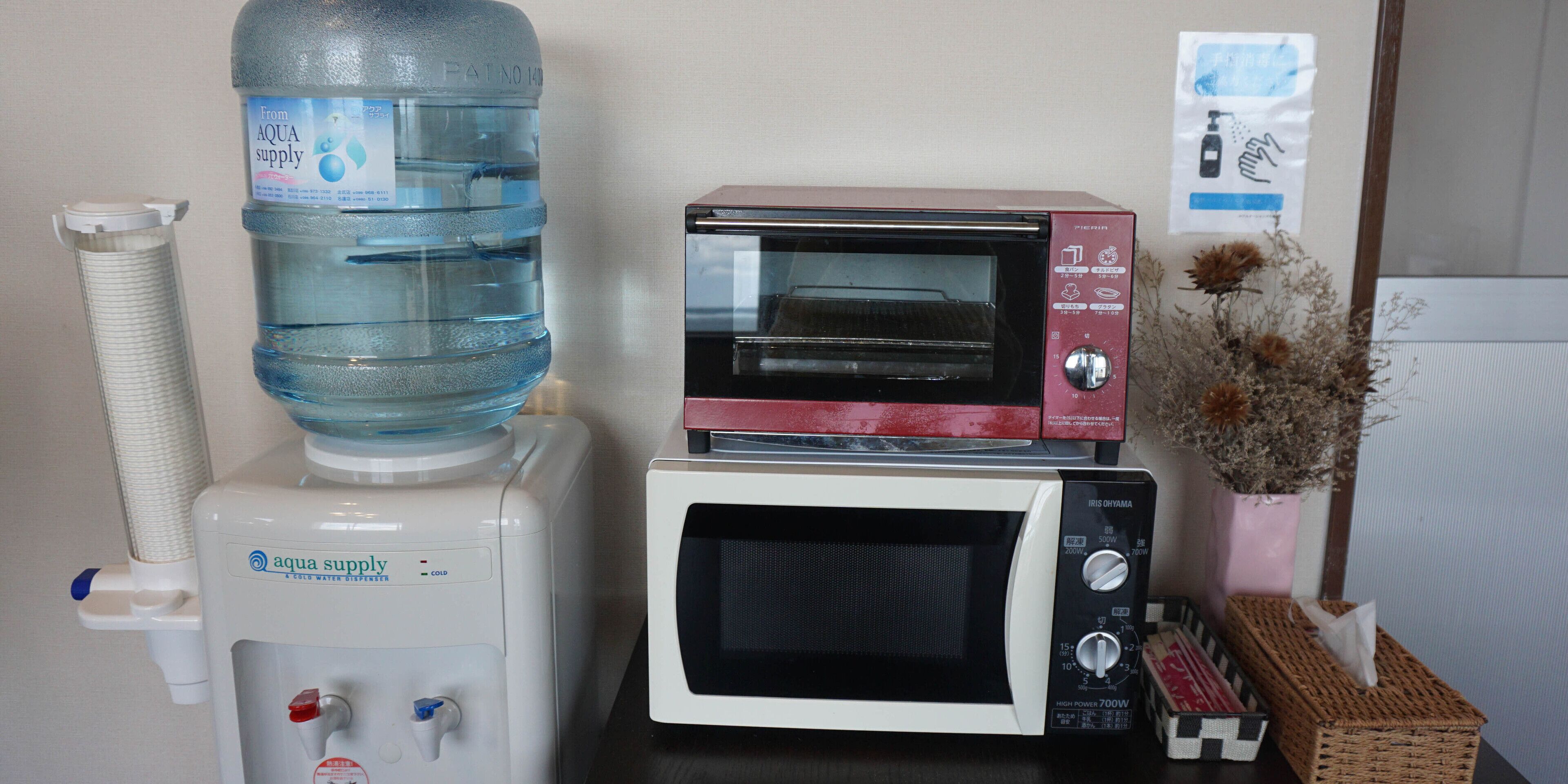 A water dispenser, a microwave, and a toaster oven stacked on a table.