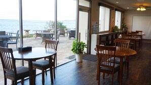 A restaurant with wooden tables and chairs, a water dispenser, and potted plants. - Hotel Oceans Nakijin (Nakijin)