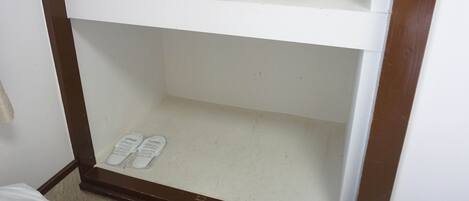 A white shelf with a pair of white slippers on it.
