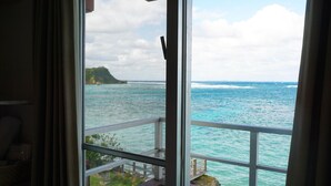 A view from a window overlooking a coastal area with a wooden deck and a rocky outcrop. - Hotel Oceans Nakijin (Nakijin)