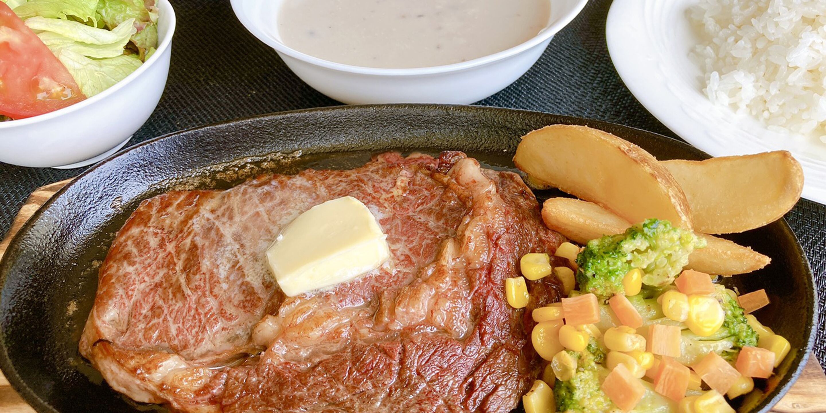 Een bord met steak, boter en groenten.
