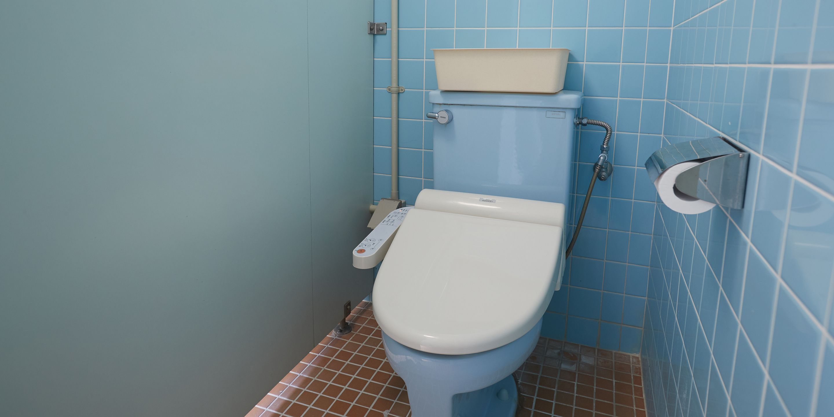 A small bathroom with a toilet, a bidet, and a toilet paper holder.