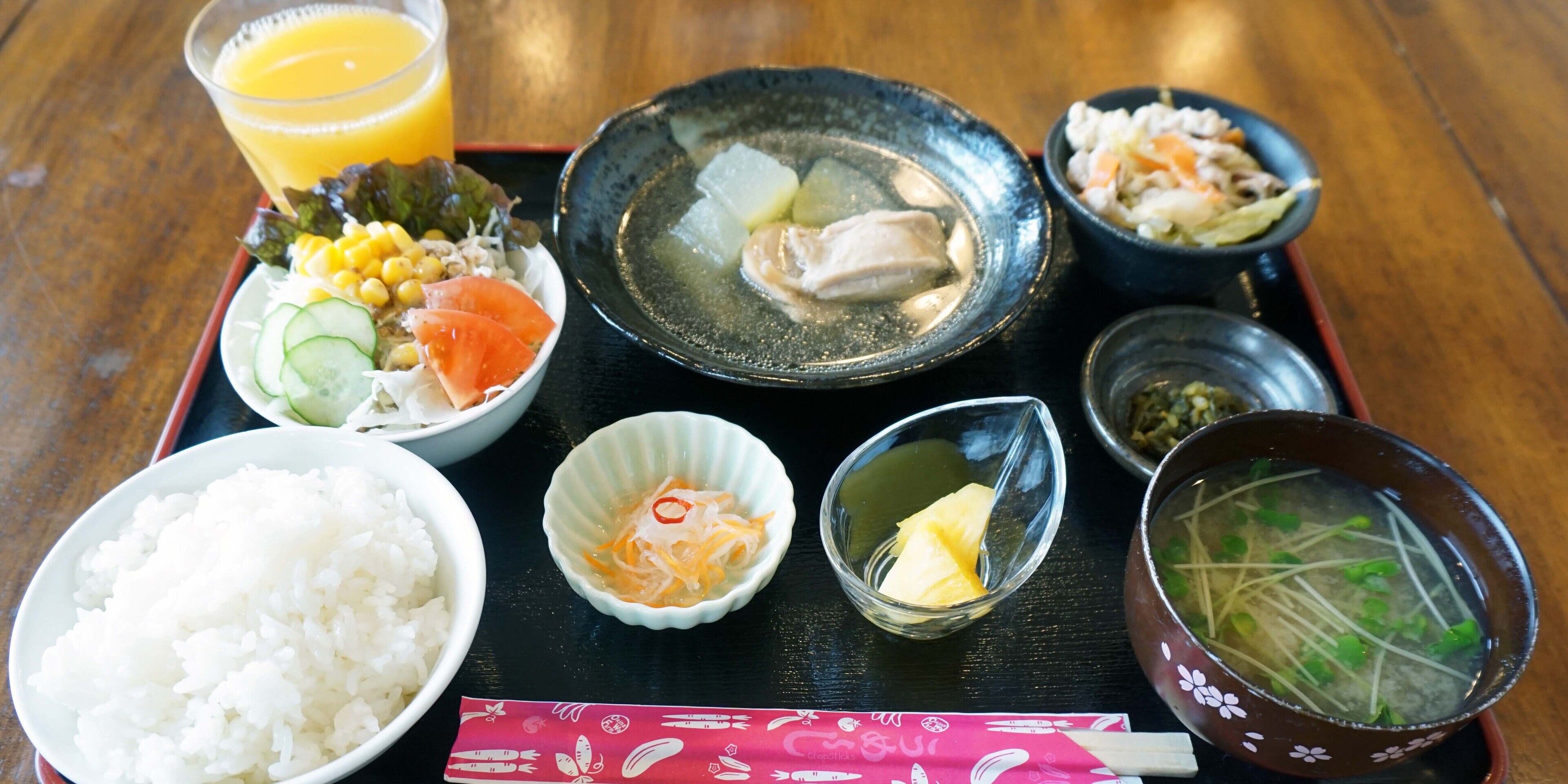 Eine traditionelle japanische Mahlzeit mit Reis, Suppe und verschiedenen Beilagen auf einem schwarzen Tablett.