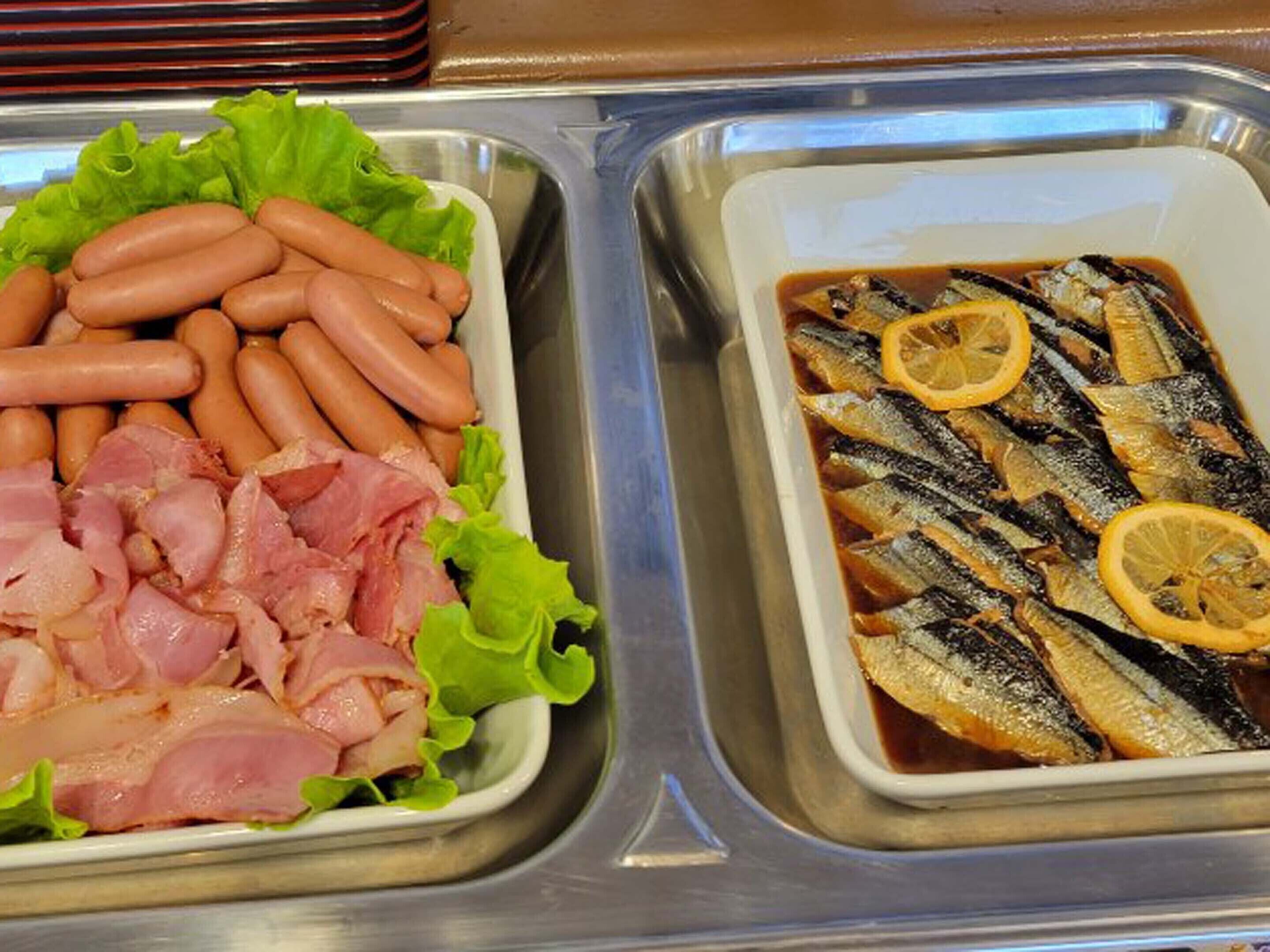 Een ontbijtbuffet met hotdogs, spek en vis.
