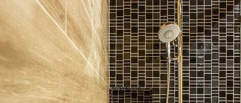 A bathroom with a shower, tiled walls, and a marble-like floor.