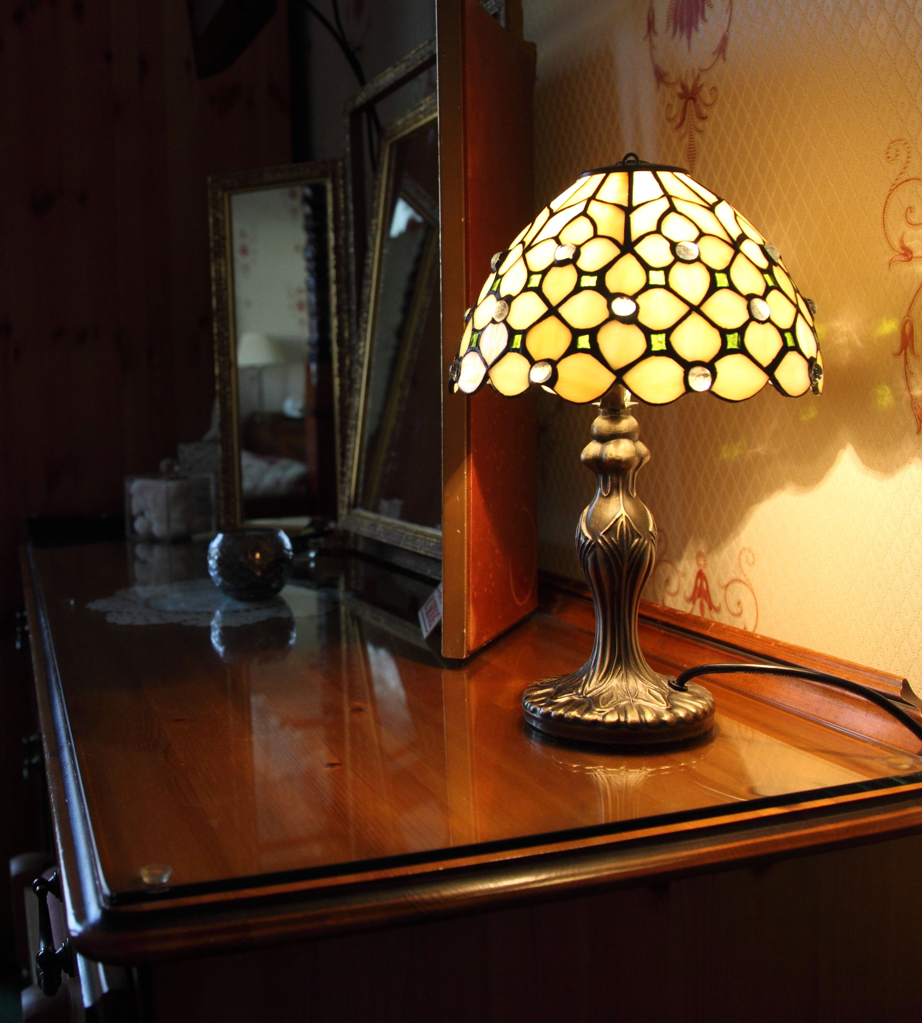 A table lamp with a unique stained glass shade on a wooden surface.