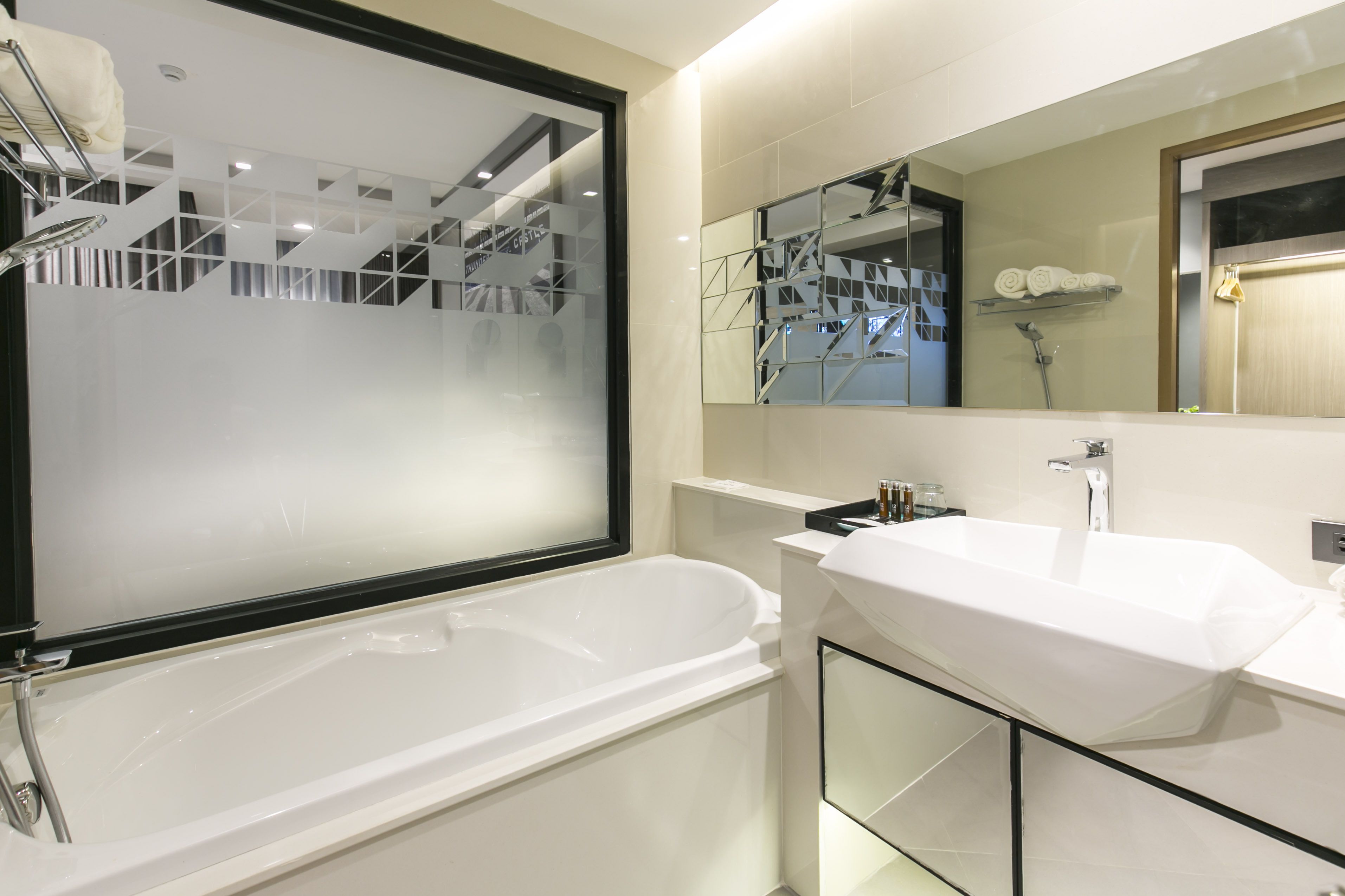 A modern bathroom with a large bathtub, a white sink, and a mirror above the sink.