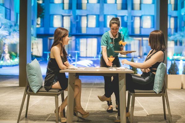 A dining area with a table, chairs, and a waiter serving drinks.