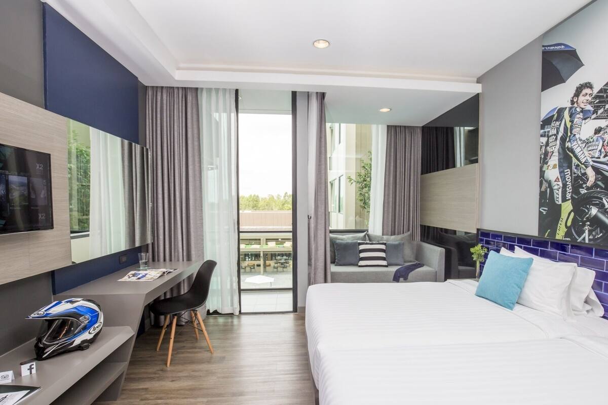 Une chambre d’hôtel avec un lit, un bureau sur lequel se trouve un casque, une télévision et un balcon avec vue.