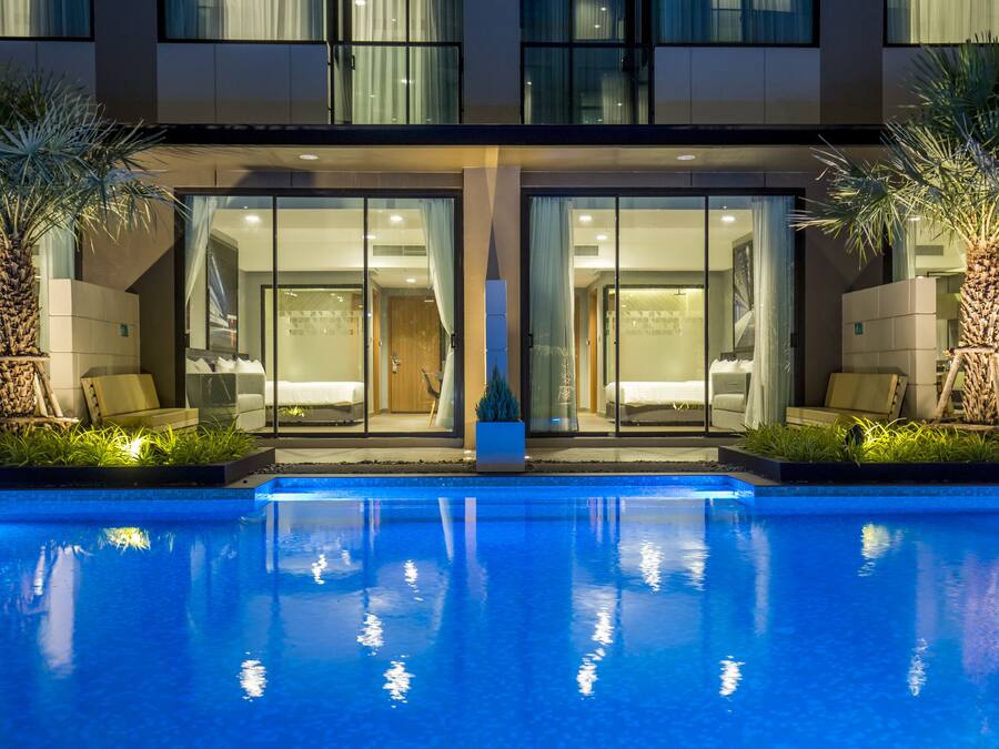 Un hotel moderno con piscina, puertas de cristal y palmeras.