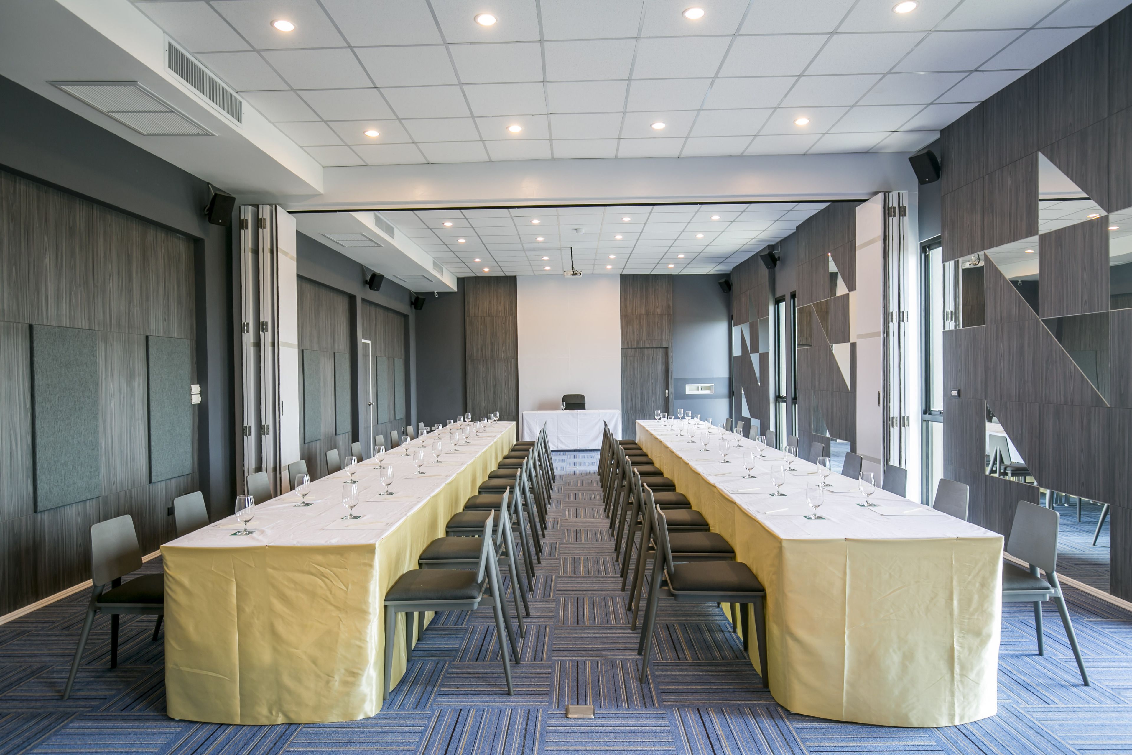 Una sala conferenze con un lungo tavolo, sedie e una tovaglia bianca.