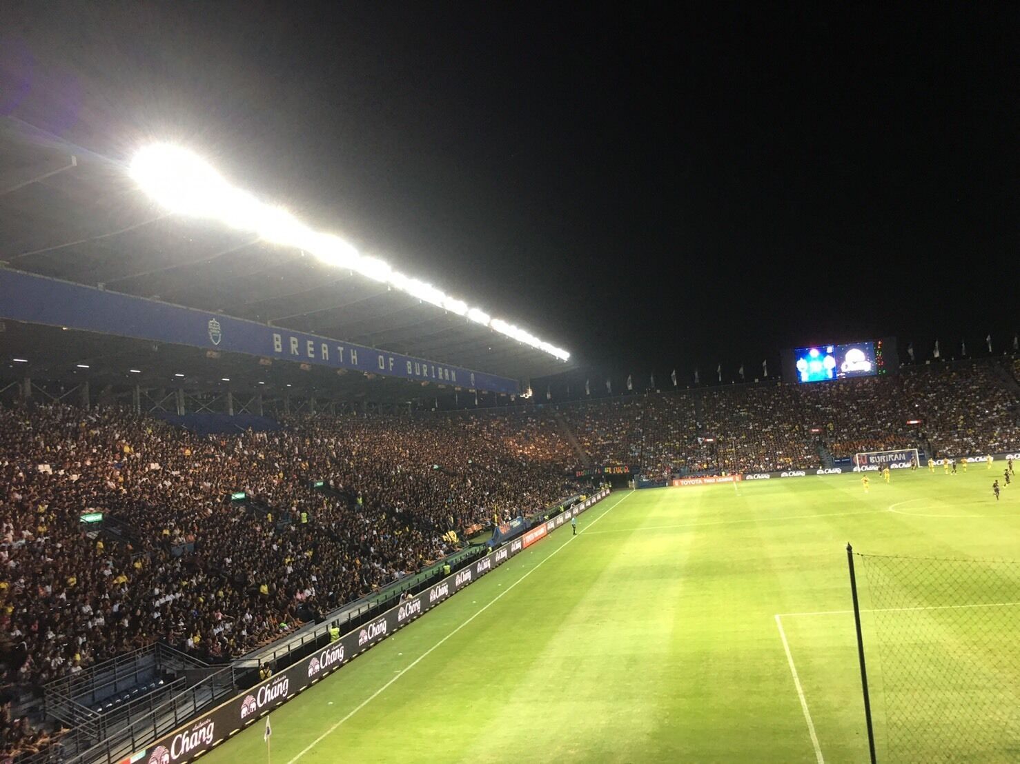 A stadium filled with spectators, a well-lit field, and a scoreboard.