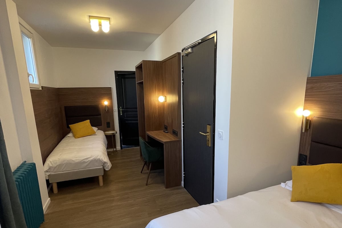 A hotel room with two beds, a desk, and a wardrobe.