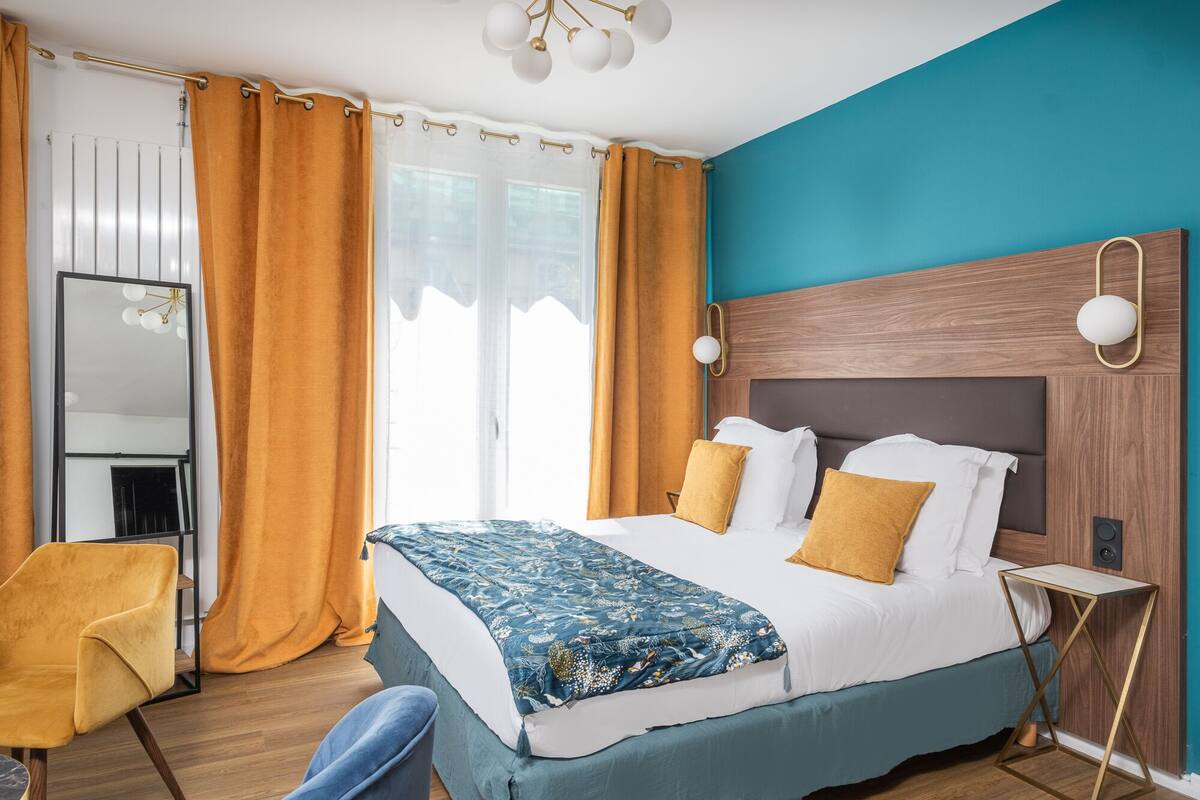 A hotel room with a large bed, a wooden headboard, a nightstand, a mirror, and a chair.