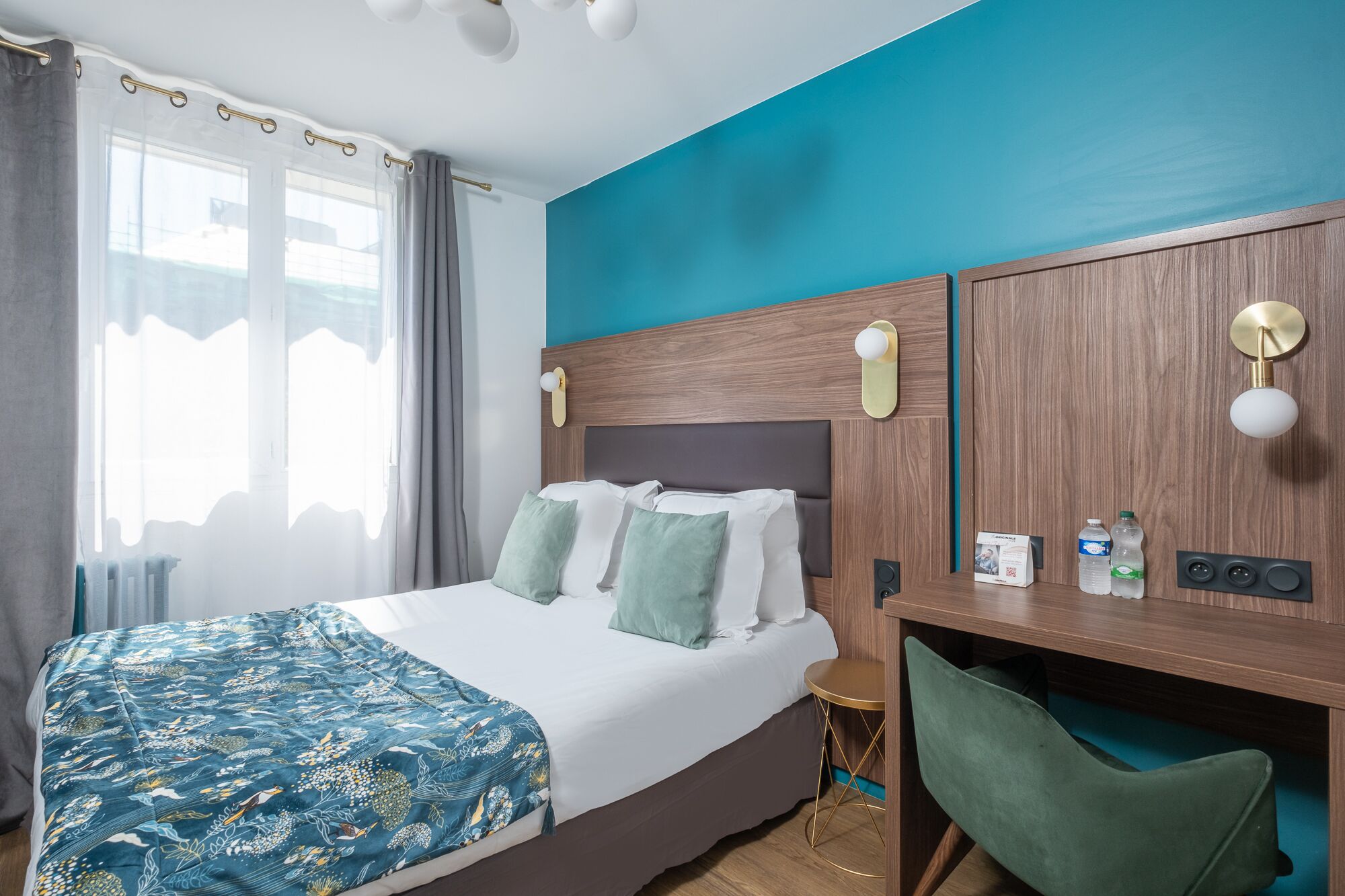 Een hotelkamer met een bed, een bureau, een stoel en een raam met gordijnen.