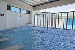 A large indoor swimming pool with multiple water jets, a digital clock, and a view of the outside. - Formosa Naruwan Galaxy Hotel Taitung (Taitung)