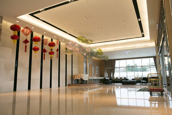 A spacious lobby with a polished floor, a reception area with seating, and decorative red lanterns.