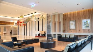 A modern lobby with black leather sofas, a stage, and wooden paneling. - Formosa Naruwan Galaxy Hotel Taitung (Taitung)