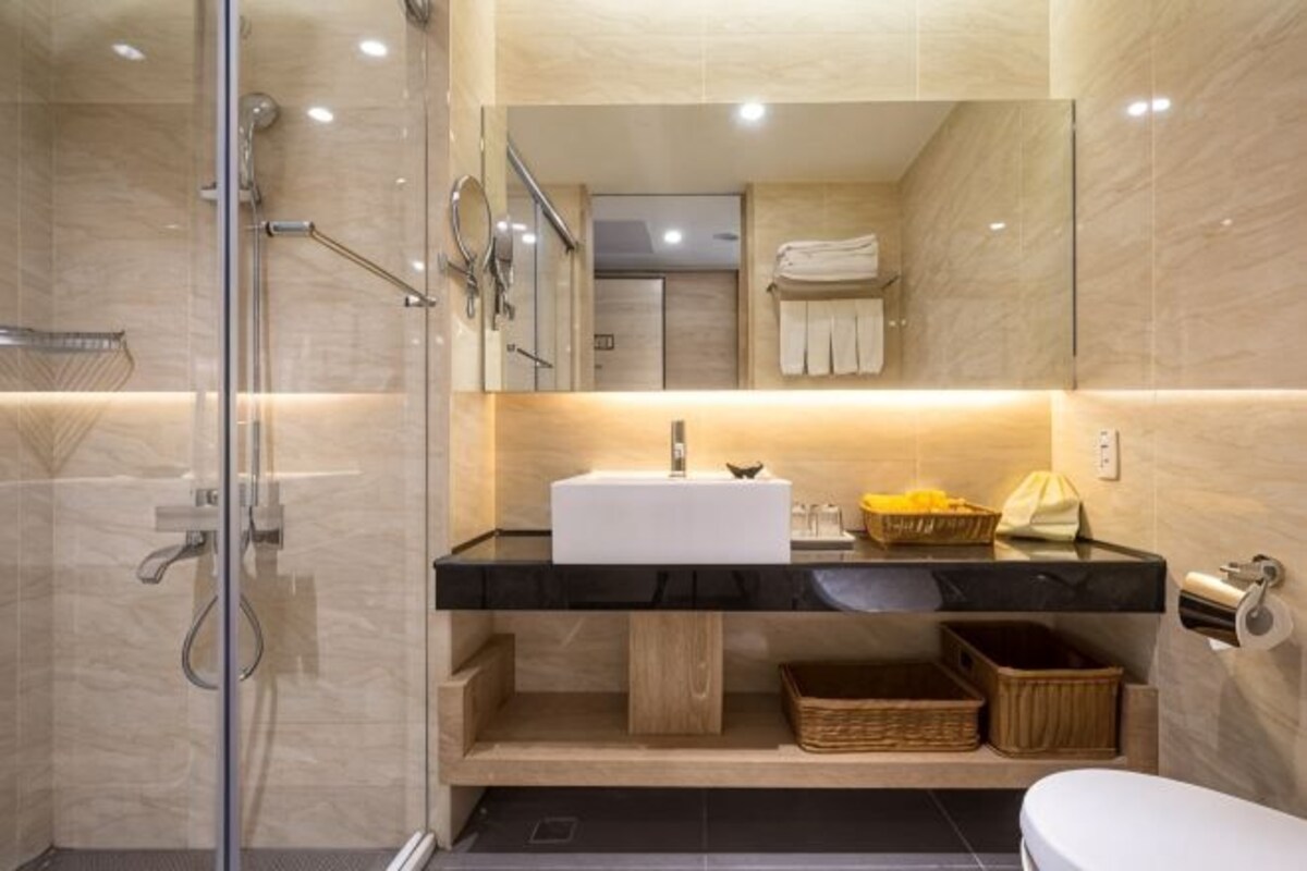 Un baño moderno con cabina de ducha de vidrio, un lavabo blanco y un espejo sobre el mueble.