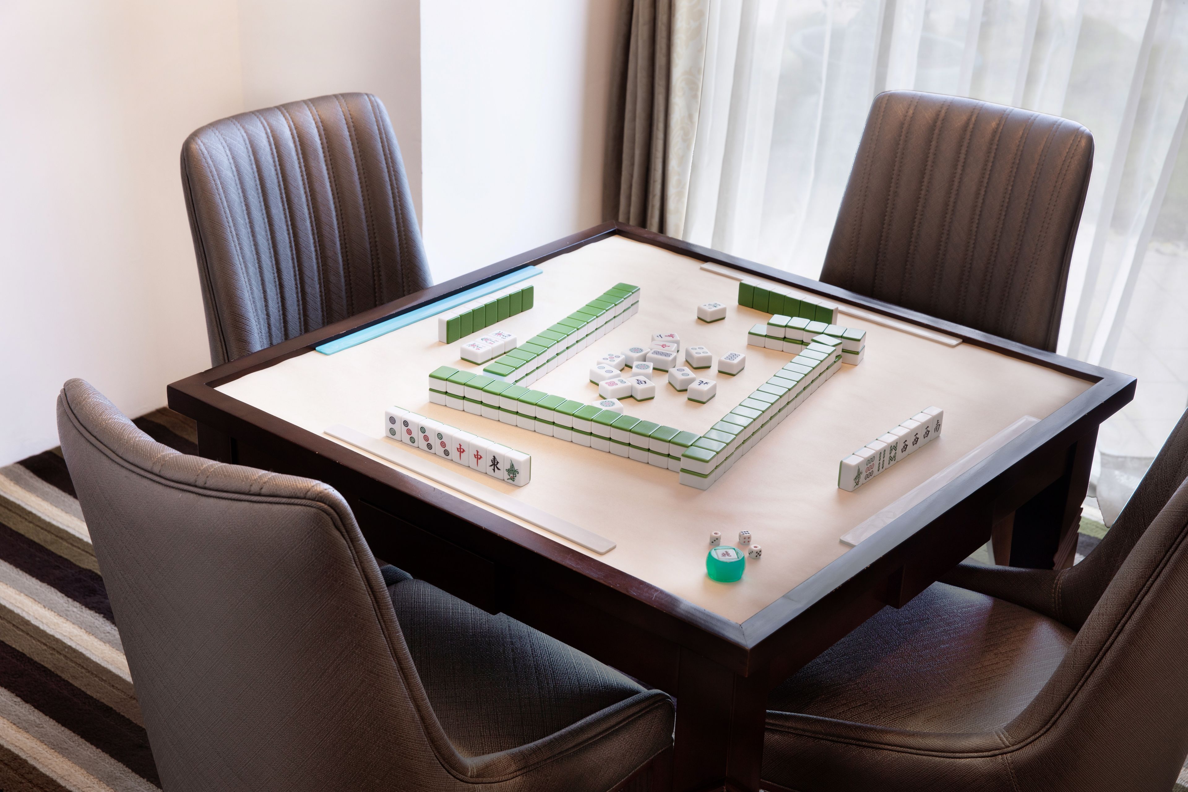 A mahjong table with tiles and a small green object on the table.